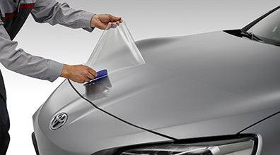 Person applying car wrap film to a Toyota vehicle