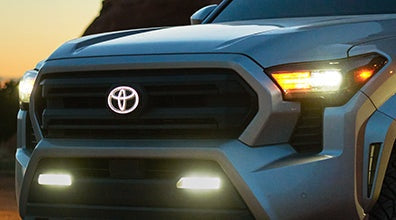 Close-up of a Toyota vehicle's front grille with headlights on.