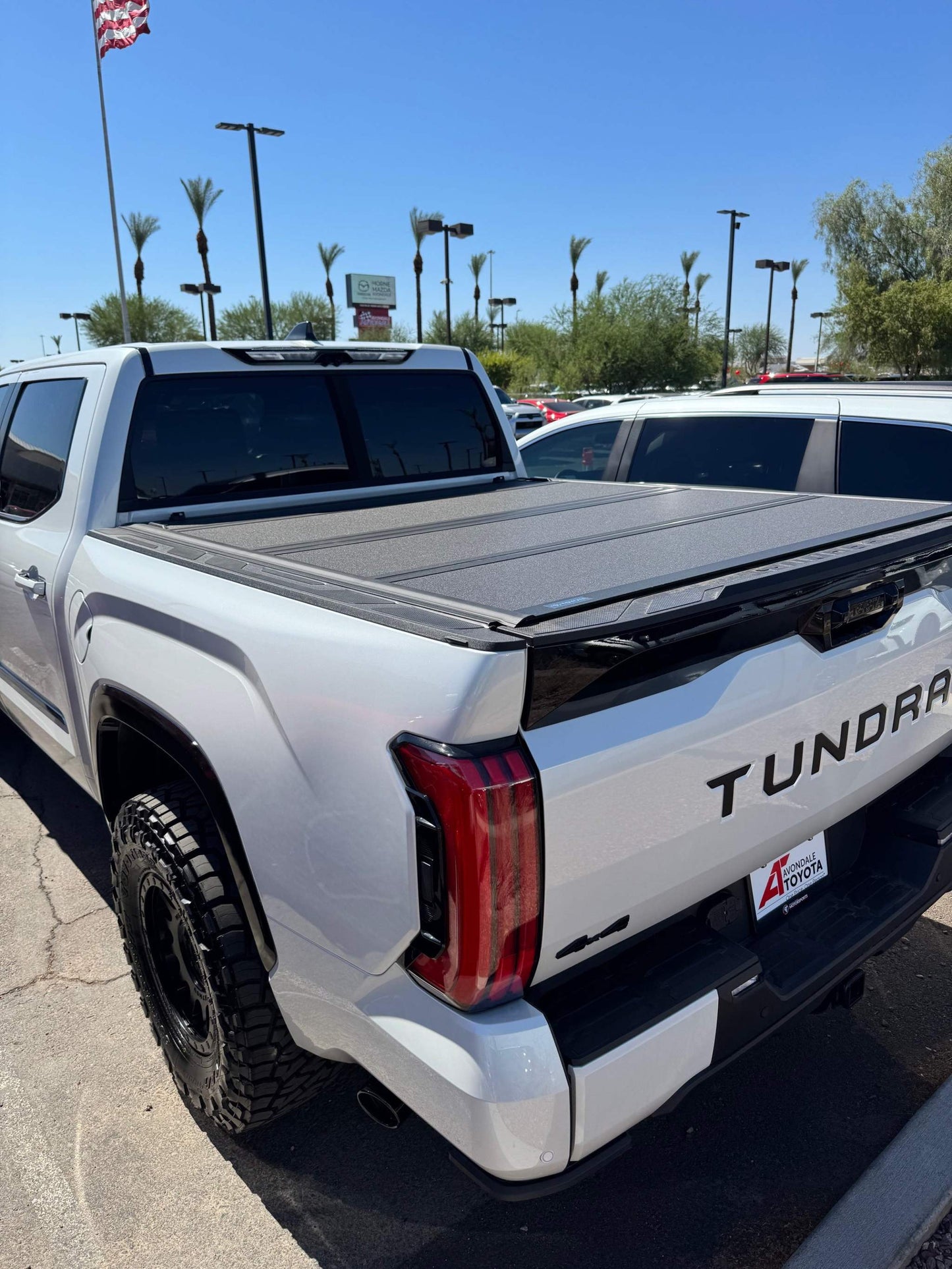 White Toyota Tundra truck with installed Tri-Fold Hard Tonneau Cover on the bed for secure, weather-resistant protection.