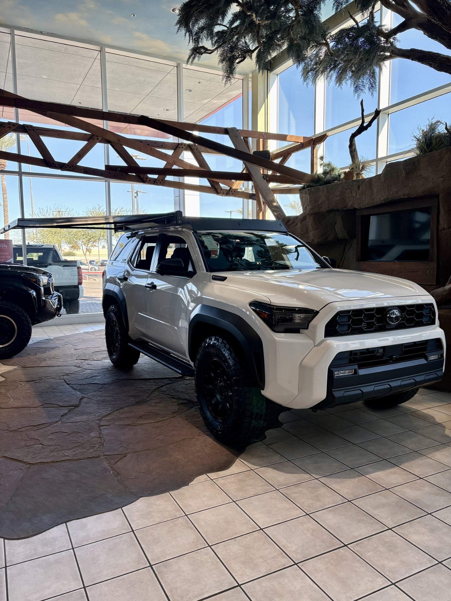 White off-road vehicle with Kammok Crosswing Awning installed indoors at dealership