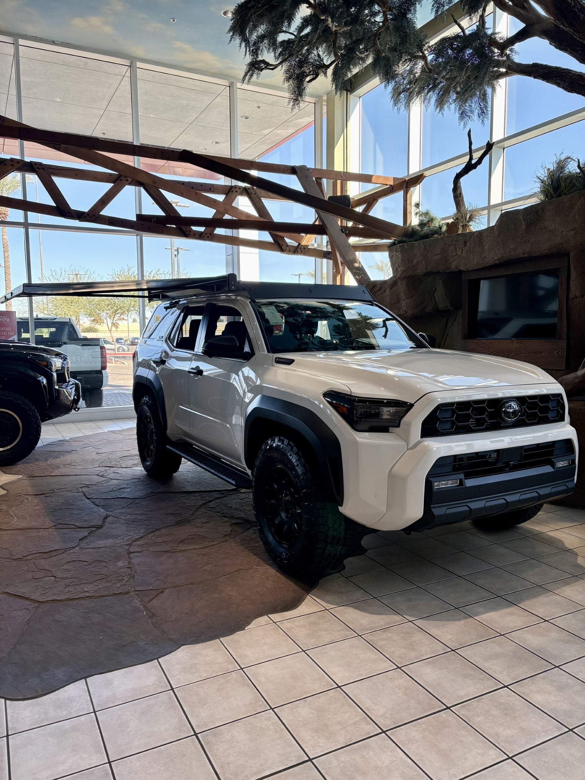 White off-road vehicle with Kammok Crosswing Awning installed indoors at dealership
